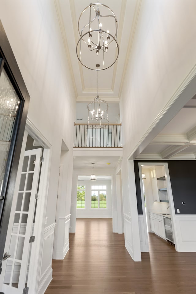 entrance foyer featuring crown molding, a notable chandelier, a high ceiling, and dark hardwood / wood-style floors