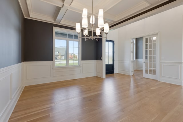 unfurnished dining area with an inviting chandelier, ornamental molding, beamed ceiling, and light hardwood / wood-style floors