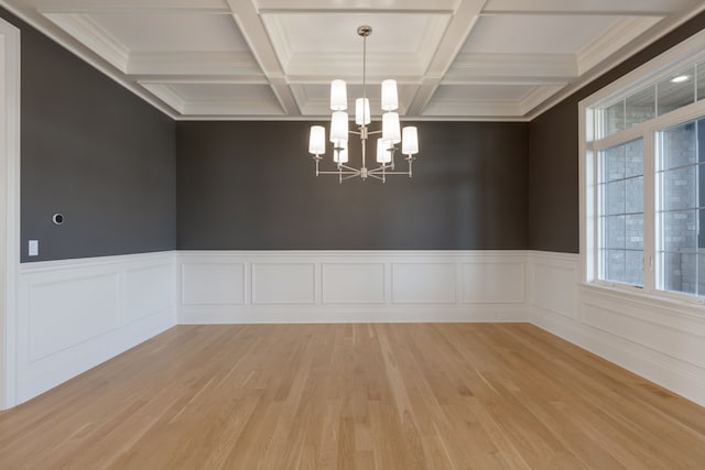 unfurnished room with hardwood / wood-style floors, coffered ceiling, beamed ceiling, crown molding, and an inviting chandelier