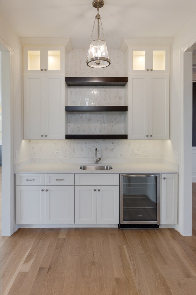 bar with sink, white cabinets, and beverage cooler