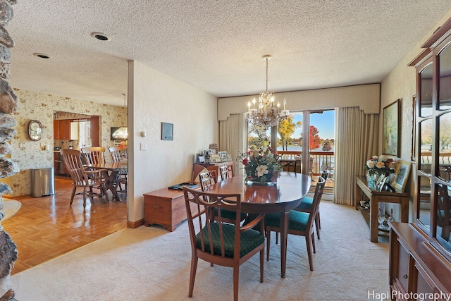 dining space with a textured ceiling, a chandelier, and light parquet flooring