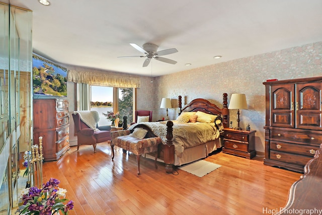 bedroom with a baseboard radiator, light wood-type flooring, and ceiling fan