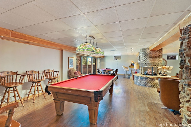 game room with a large fireplace, a drop ceiling, pool table, and hardwood / wood-style floors