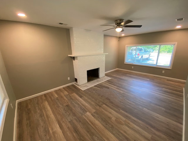 unfurnished living room featuring a fireplace, dark wood-type flooring, and ceiling fan