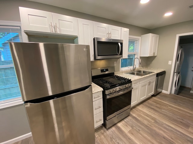 kitchen with appliances with stainless steel finishes, sink, light hardwood / wood-style floors, and white cabinets