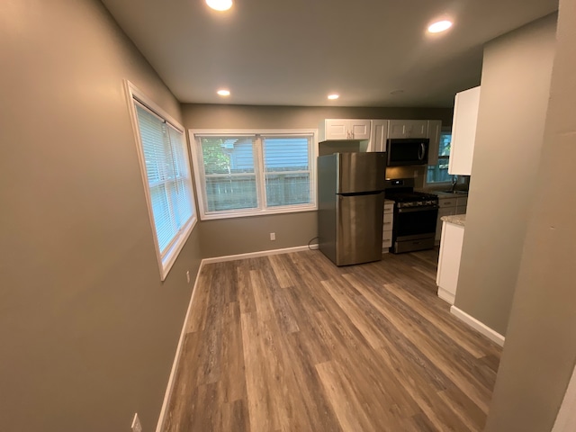 kitchen with white cabinets, appliances with stainless steel finishes, hardwood / wood-style flooring, and sink