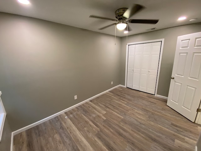 unfurnished bedroom featuring ceiling fan, dark hardwood / wood-style floors, and a closet