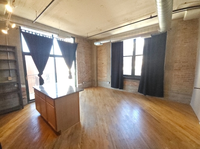 kitchen with light hardwood / wood-style floors, brick wall, and a center island