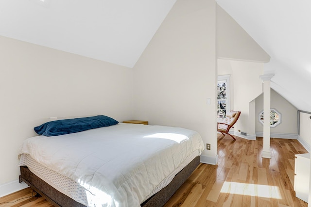 bedroom featuring wood finished floors, baseboards, and high vaulted ceiling