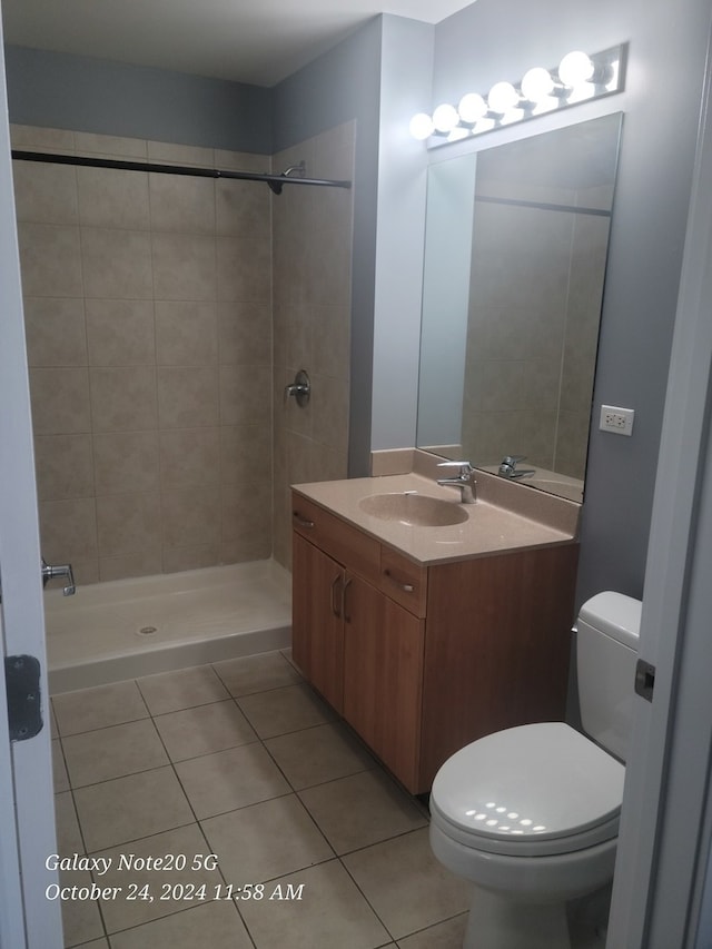 bathroom featuring vanity, toilet, tile patterned floors, and tiled shower