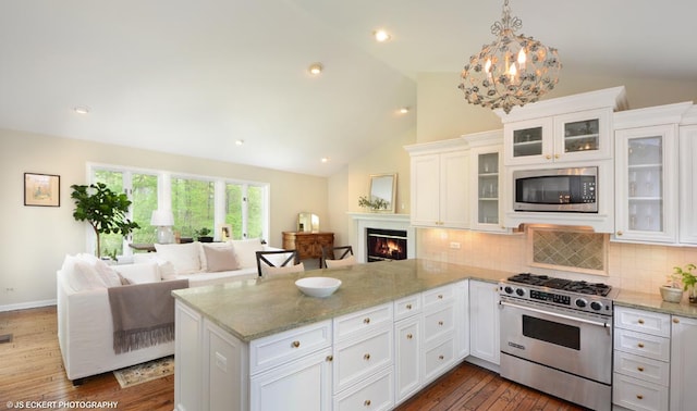 kitchen featuring kitchen peninsula, appliances with stainless steel finishes, pendant lighting, white cabinets, and dark hardwood / wood-style floors