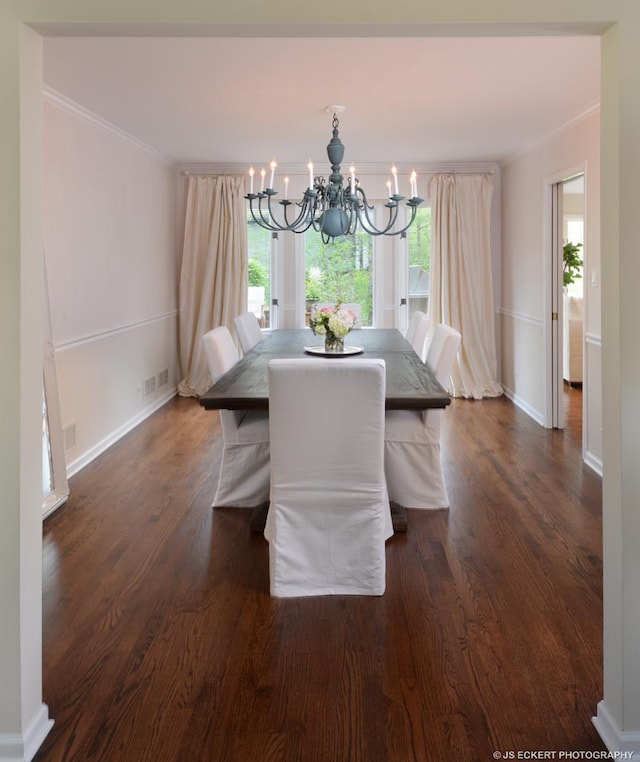 dining area featuring crown molding, dark wood-type flooring, and a chandelier