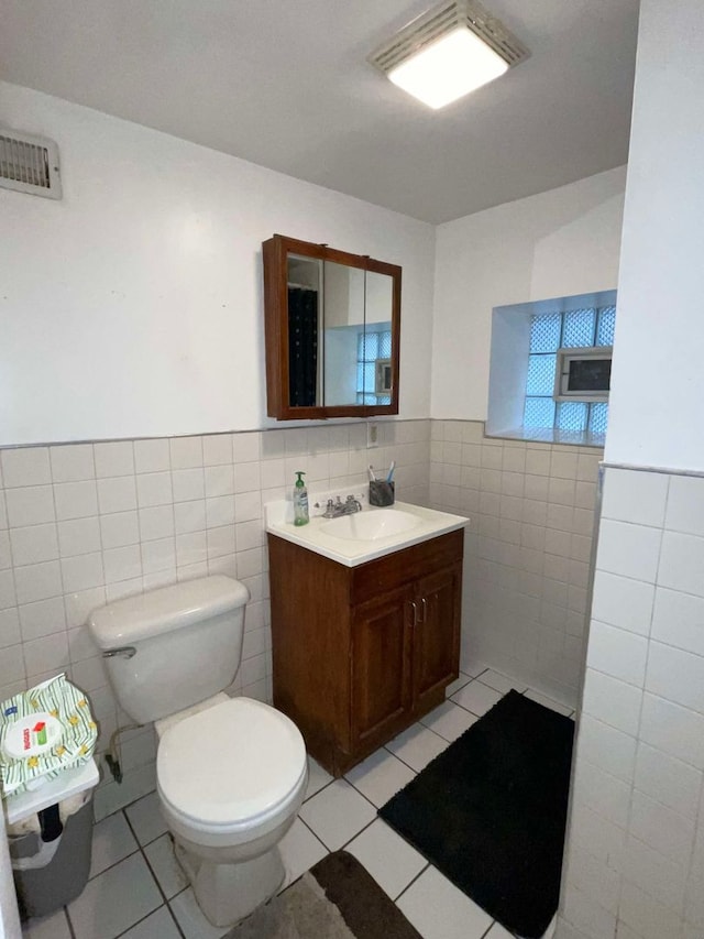 bathroom featuring vanity, toilet, tile walls, and tile patterned flooring