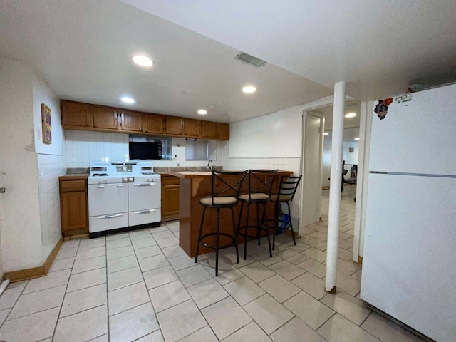 kitchen with white appliances, kitchen peninsula, and a kitchen breakfast bar