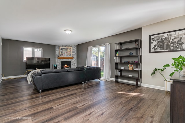 living room featuring a stone fireplace and dark hardwood / wood-style floors