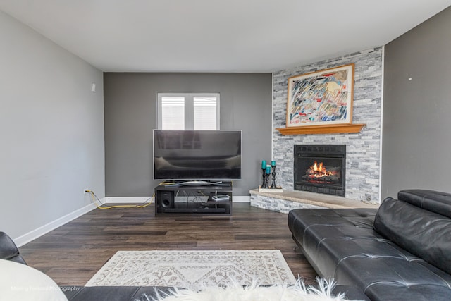 living room with a stone fireplace and dark hardwood / wood-style floors