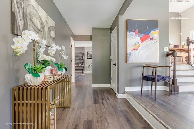 hallway with dark hardwood / wood-style floors and an inviting chandelier