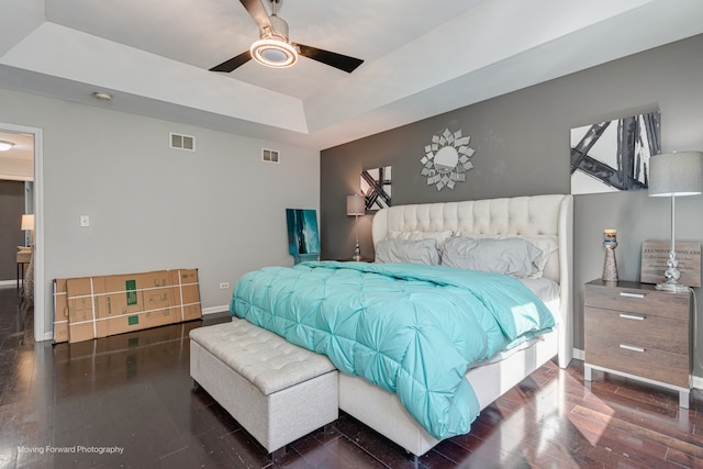 bedroom with a raised ceiling, ceiling fan, and dark hardwood / wood-style flooring