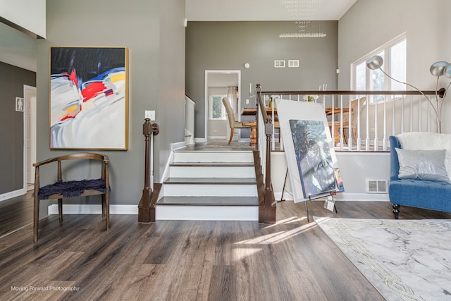 stairs featuring wood-type flooring, a wealth of natural light, and a chandelier