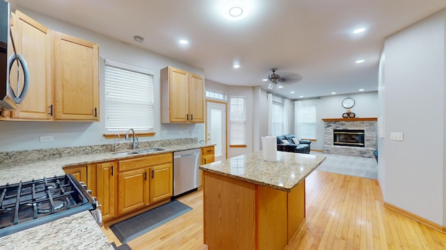 kitchen featuring light hardwood / wood-style floors, sink, appliances with stainless steel finishes, light stone countertops, and a kitchen island