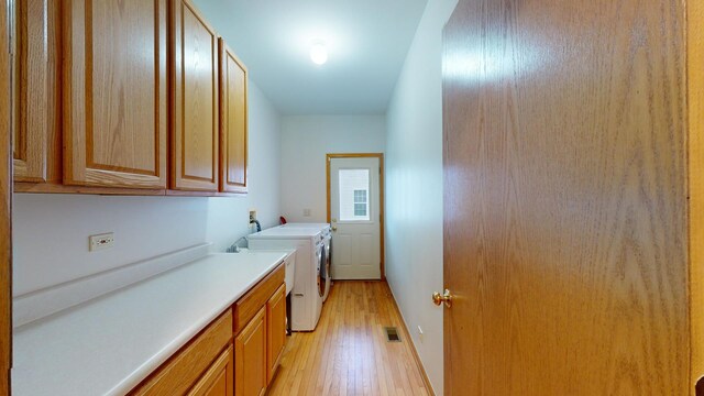 laundry area with light hardwood / wood-style flooring, cabinets, and independent washer and dryer