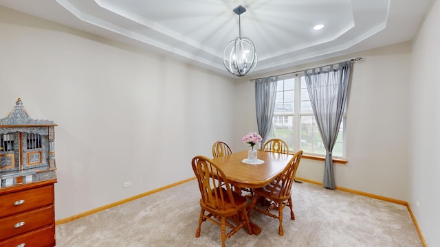 dining area with light carpet, a raised ceiling, and an inviting chandelier