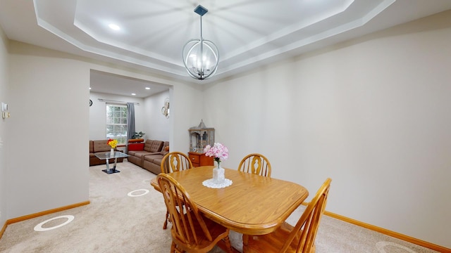 carpeted dining area featuring a chandelier and a tray ceiling