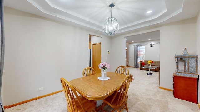 dining room featuring a tray ceiling, an inviting chandelier, and light colored carpet