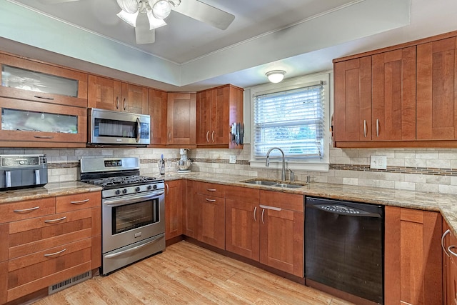 kitchen featuring light stone countertops, sink, light hardwood / wood-style flooring, decorative backsplash, and appliances with stainless steel finishes