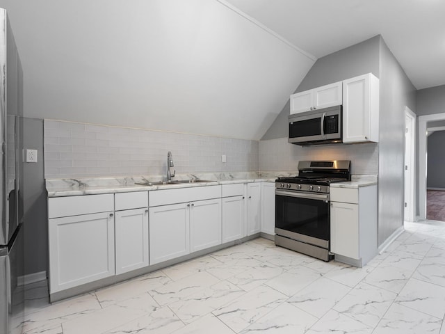 kitchen featuring tasteful backsplash, stainless steel appliances, sink, white cabinetry, and lofted ceiling