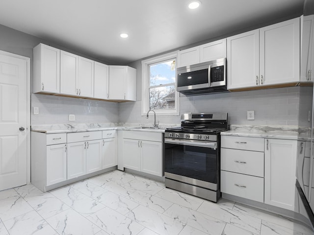 kitchen featuring appliances with stainless steel finishes, tasteful backsplash, white cabinetry, and sink