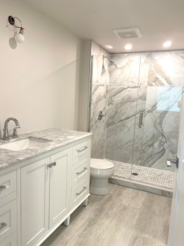 bathroom with vanity, hardwood / wood-style floors, walk in shower, and toilet