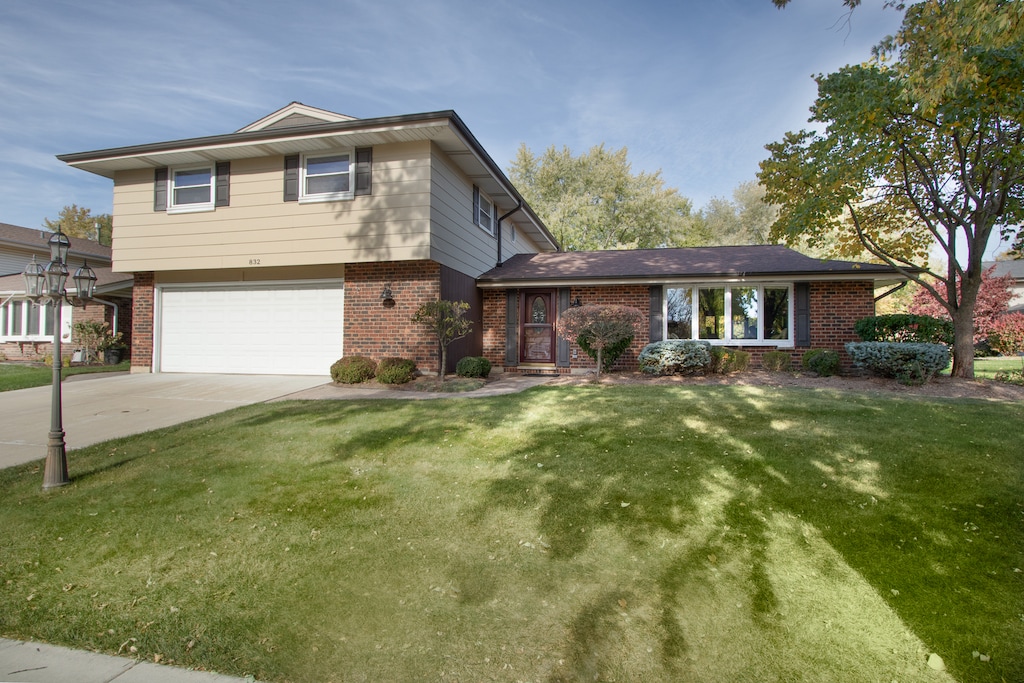 split level home with a garage and a front lawn