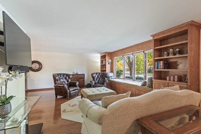 living room with built in shelves and hardwood / wood-style floors