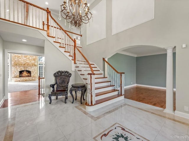 stairs featuring a towering ceiling, crown molding, decorative columns, and wood-type flooring
