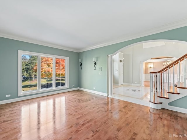 unfurnished living room featuring light hardwood / wood-style flooring, ornamental molding, and a notable chandelier