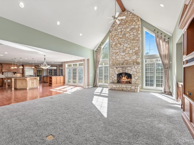 unfurnished living room featuring light colored carpet, a healthy amount of sunlight, beamed ceiling, and high vaulted ceiling