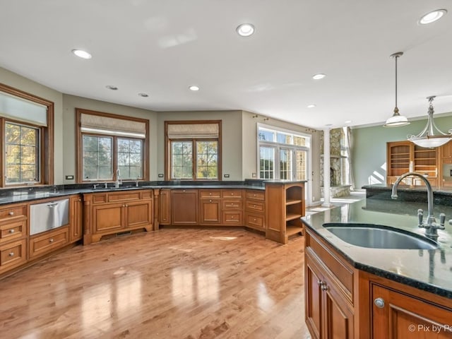kitchen featuring sink, hanging light fixtures, light hardwood / wood-style floors, and dark stone counters