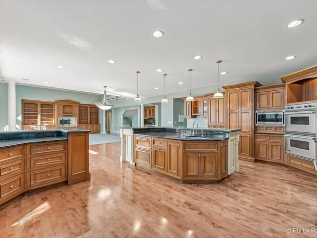 kitchen featuring a kitchen island with sink, light hardwood / wood-style flooring, sink, pendant lighting, and stainless steel appliances