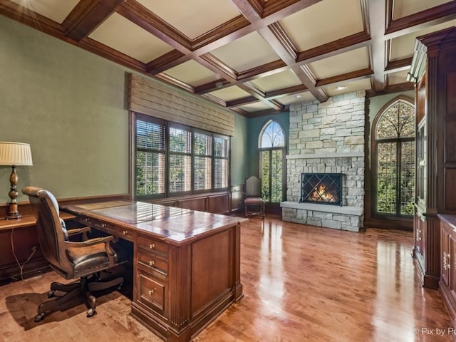 office with coffered ceiling, beam ceiling, a stone fireplace, and light wood-type flooring