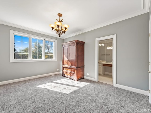 unfurnished bedroom with crown molding, light colored carpet, a chandelier, and ensuite bath