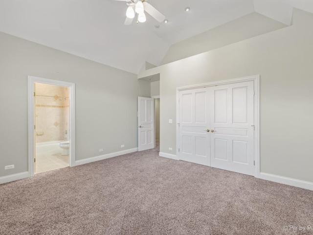 unfurnished bedroom with a closet, light carpet, ensuite bathroom, high vaulted ceiling, and ceiling fan