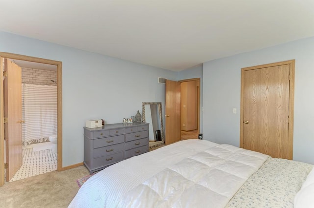 bedroom featuring ensuite bathroom and light carpet