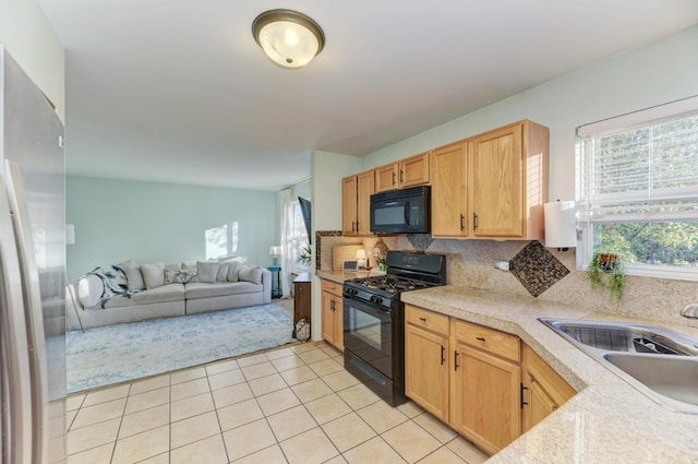 kitchen featuring black appliances, sink, tasteful backsplash, light tile patterned flooring, and light brown cabinetry