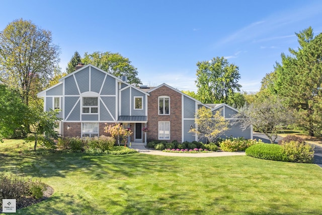 tudor home featuring a front lawn, a chimney, and brick siding