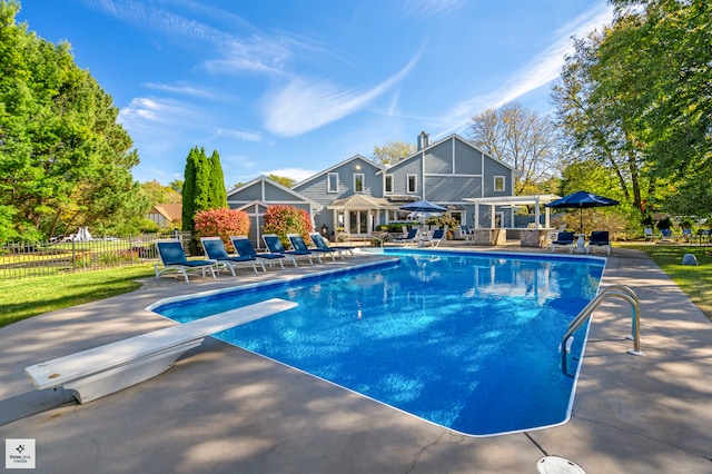 view of swimming pool with a patio area and a diving board