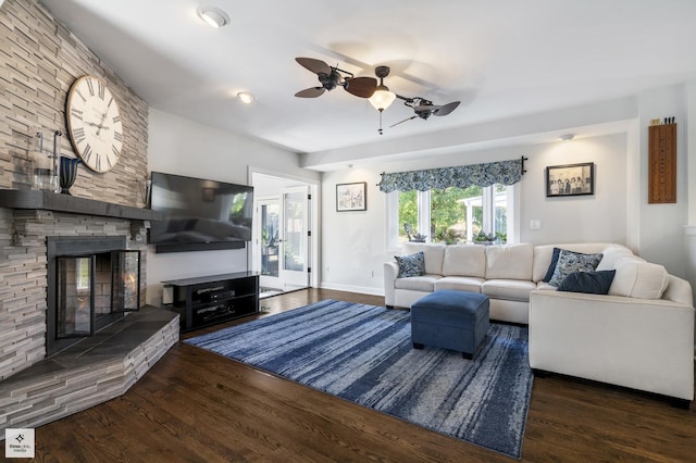 living room with wood finished floors, a ceiling fan, and a stone fireplace