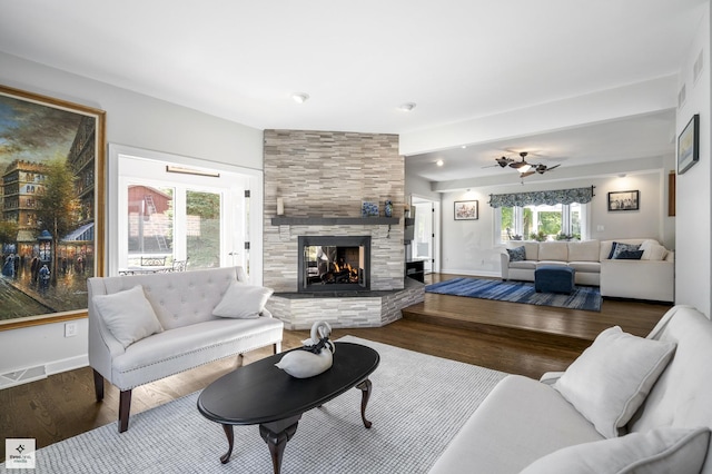 living room featuring a fireplace, wood finished floors, visible vents, and baseboards