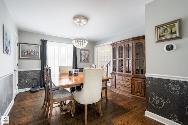dining room featuring dark wood-style flooring, a chandelier, a wainscoted wall, and baseboards