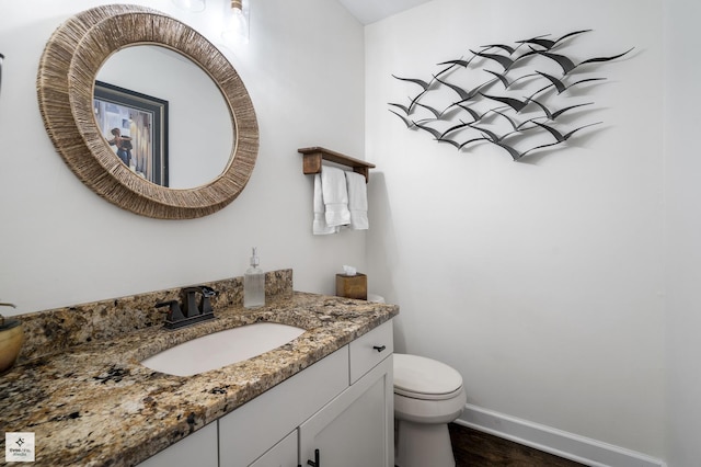 bathroom featuring toilet, wood finished floors, vanity, and baseboards